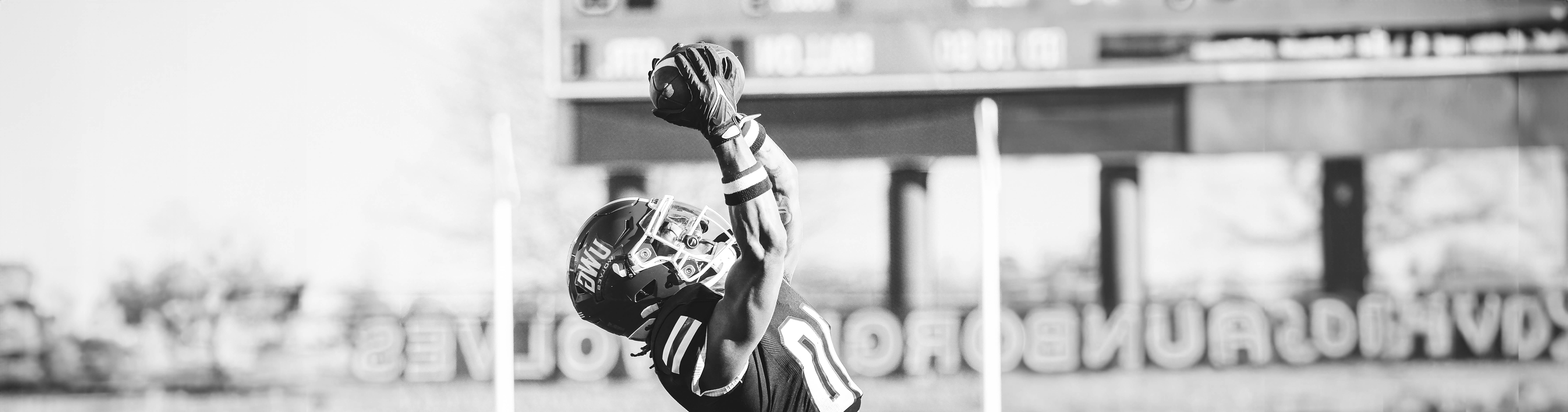 在线博彩 Football Player jumping into the air to catch the football.